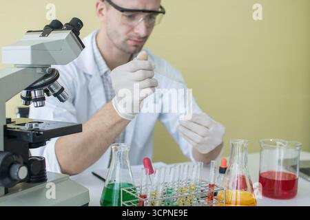 Medical or scientific researcher or man doctor looking at a test tube of clear solution in a laboratory Stock Photo