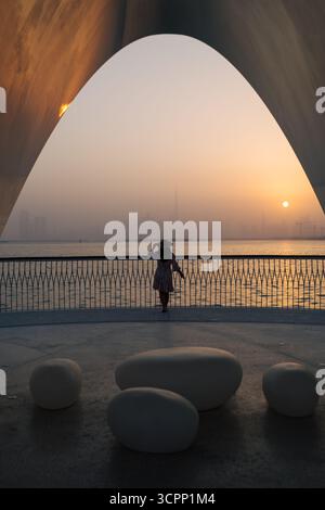 back view of Tourist woman enjoying sunset at Dubai creek harbor promenade, silhouette skyline 4k wallpaper background- vertical Stock Photo