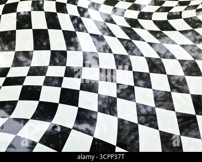 Distorted checkered pattern with a wavy, warped surface creating an abstract black and white optical illusion Stock Photo