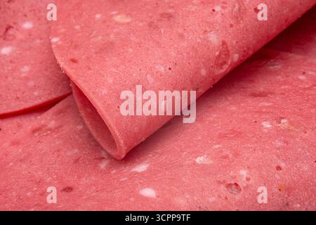 A close-up image of finely sliced deli meat. Showcasing its smooth texture and vibrant pink color. The layers of meat overlap. Emphasizing the quality Stock Photo