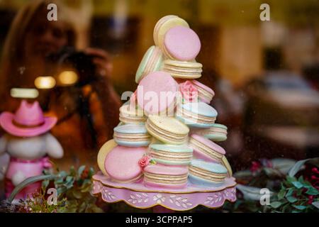 Colorful macarons stacked on a decorative stand in a pastry shop, close-up with blurred background. Stock Photo
