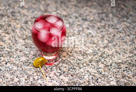 Chilled red cocktail with ice and olive garnish. A vibrant red cocktail served in a rounded glass. A olive garnish on a toothpick. Stock Photo