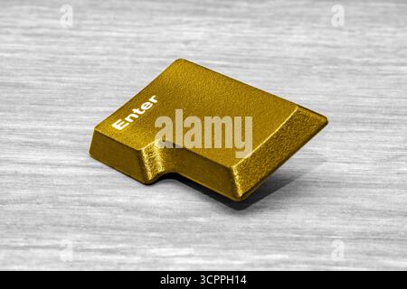 Golden enter key on wooden surface. Modern and luxurious aesthetic, symbolizing success, exclusivity, and digital transformation. Stock Photo
