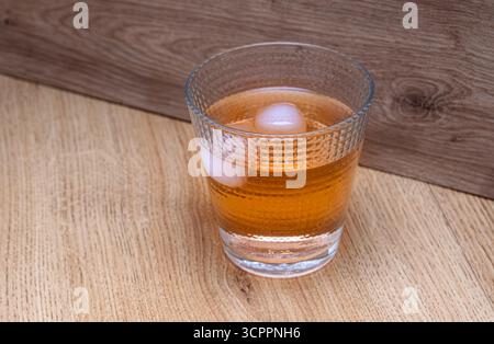 Chilled beverage in a textured glass on wooden surface. The intricate pattern of the glass enhances the visual appeal a warm atmosphere. Stock Photo