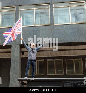 LONDON, UK. 13th August 2025. UNITE THE KINGDOM PROTEST" Protester stands on a bus shelter. Waving a Union Jack flag. Photo Credit: Ian Humphreys Stock Photo
