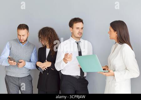 Focused interested happy young colleagues talking to boss team leader, explaining working issues Stock Photo