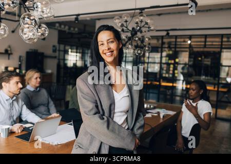 Portrait of happy female business professional wearing blazer standing in office Stock Photo