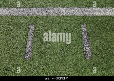 Top view of straight short and long white spray painted lines on green artificial grass on multiple use sports field. Stock Photo