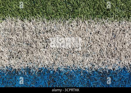 Close-up and top view of blue and white spray painted parallel lines on artificial grass on multiple use sports field. Stock Photo