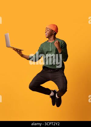 Online Win. Excited Happy Black Guy Jumping Up With Laptop Computer Stock Photo