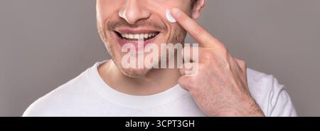 Smiling man moisturizing face with crea,. close up portrait Stock Photo