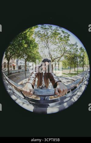 Fashionable young man posing near railing at park in Fish Eye photo Stock Photo