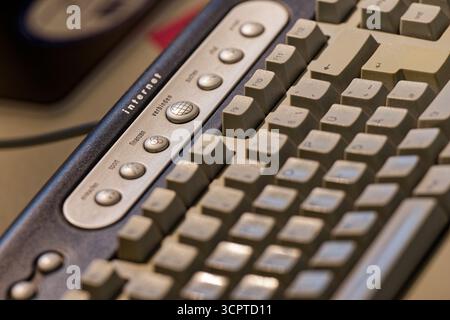 A dark gray retro keyboard shows lighter keys and a key labeled Internet, the matte surface reveals gentle wear on caps, a close view of everyday tech Stock Photo