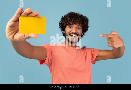 Cheerful young indian man pointing at credit card Stock Photo