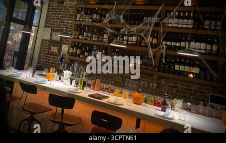 Halloween-Themed Bar Interior with Pumpkin, Cobwebs and Wine Bottles on Brick Wall Shelves Stock Photo
