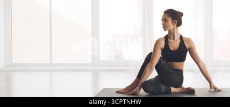 Woman practicing yoga in a bright studio with large windows Stock Photo