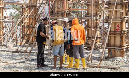 Construction workers discuss on site, reviewing project plans to maintain good coordination and teamwork in building progress. Stock Photo