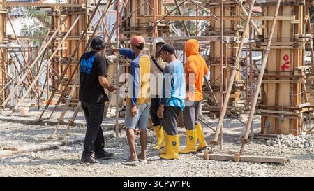 Construction workers discuss on site, reviewing project plans to maintain good coordination and teamwork in building progress. Stock Photo