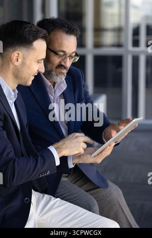 Two businessmen collaborating and reviewing project details on digital tablet Stock Photo