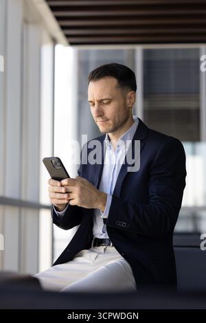 Serious businessman using smart phone at workplace Stock Photo