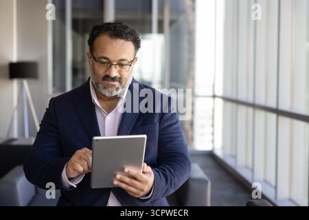 Mature Indian businessman working on wireless digital tablet device Stock Photo