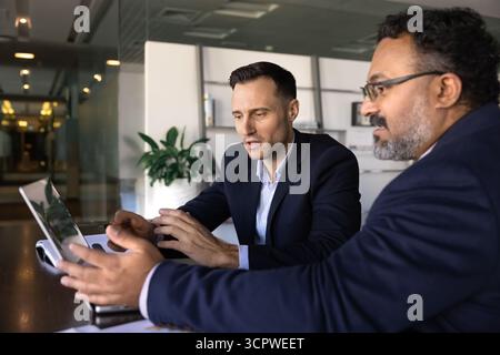Two focused businessmen working together on laptop in modern office Stock Photo