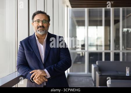 Professional male executive dressed in suit posing in contemporary workspace Stock Photo