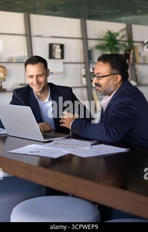 Two businessmen discussing business performance data displayed on laptop Stock Photo