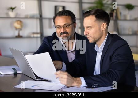 Two focused businessmen reviewing document, collaborating on financial report Stock Photo