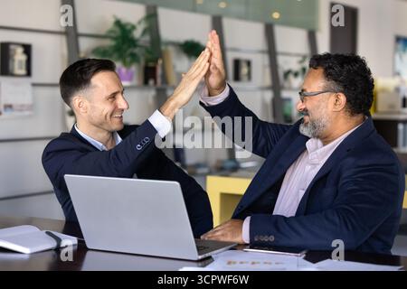 Two business partners enthusiastically giving each other high five Stock Photo