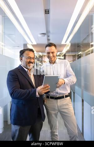 Two successful businessmen stand in modern hallway with tablet Stock Photo