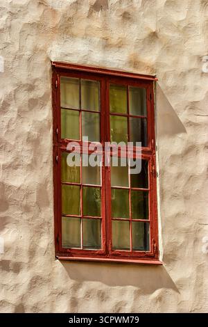 Red window on a white wall with shadows Stock Photo