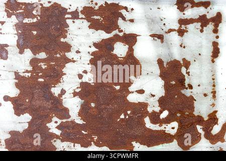 Rust spreading on a metal surface, forming irregular reddish-brown patches and abstract organic patterns over a white background Stock Photo