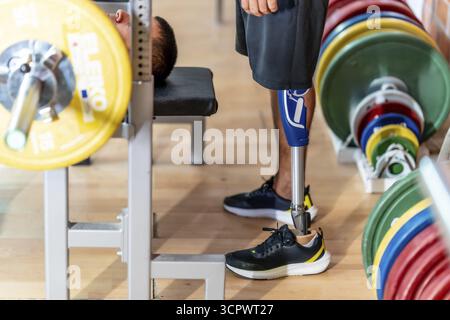 Adaptive athlete with a prosthetic leg doing weightlifting exercises on a gym bench, demonstrating strength, determination, and overcoming physical ch Stock Photo