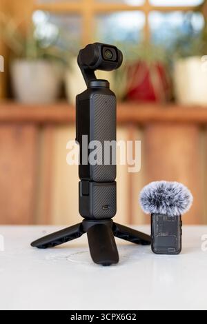 Handheld Gimbal Camera with Tripod and Wireless Microphone on White Table with Blurred Background Stock Photo