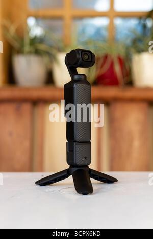 Compact Handheld Gimbal Camera Mounted on Mini Tripod on Wooden Table with Blurred Background. Stock Photo