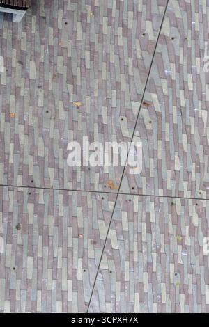 A top-down, abstract view of a mirrored surface reflecting a pattern of gray and dark textured paving stones or cobbles. Stock Photo
