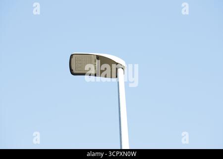 A street lamp against a clear blue sky. The lamp is modern, with an LED array. Stock Photo