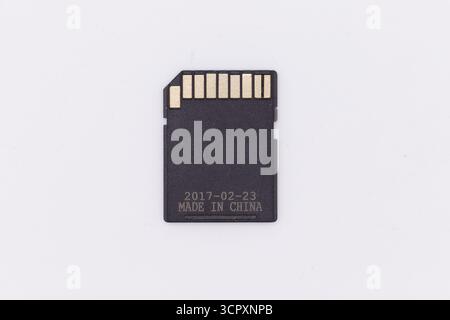 Close-up of a black SD card centered on a white background, featuring gold connectors and printed text "2017-02-23 MADE IN CHINA." Stock Photo