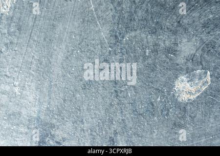 Close-up of a scratched, gray, textured surface. A light-colored, irregular area is visible in the bottom right. Stock Photo