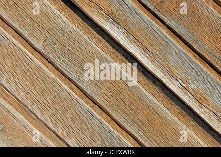 The image shows a close-up view of weathered wooden planks arranged diagonally, with gaps revealing a light-colored fill. Stock Photo