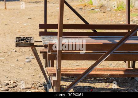A picnic table with attached benches and a grill is centered in the frame. The table and benches are constructed of wood and metal supports. Stock Photo