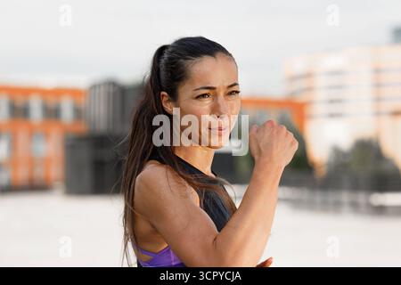 Young female athlete practicing punches outdoors, standing on the roof Young female athlete practicing punches outdoors, standing on the roof Russia C Stock Photo