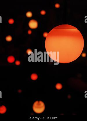 Glowing orange spherical lights against a dark background, creating an abstract and atmospheric pattern. Stock Photo
