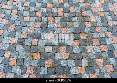 A street paved with multicolored cobblestones, viewed from above. Beautiful background. The texture of the stone sidewalk. Stock Photo