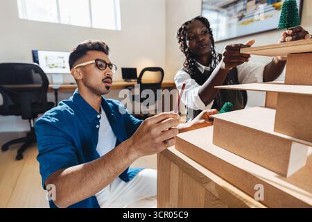 Two architects working together designing a detailed project model in a creative workspace. Collaboration and professionalism are evident as they focu Stock Photo