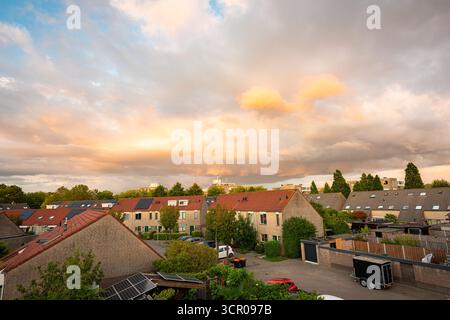 Warm evening light over a quiet dutch suburb with rows of houses beneath a colourful sky Stock Photo