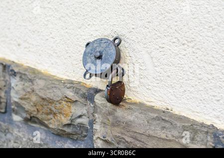 Rusty lock hanging on wall bracket old security system Stock Photo