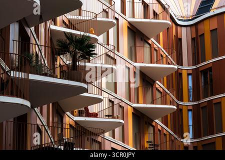 Curved modern apartment facade with layered balconies, warm tones, and dynamic architectural rhythm Stock Photo