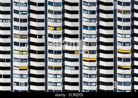 Geometric facade of modern residential tower with repeating balconies and windows featuring yellow accent panels Stock Photo